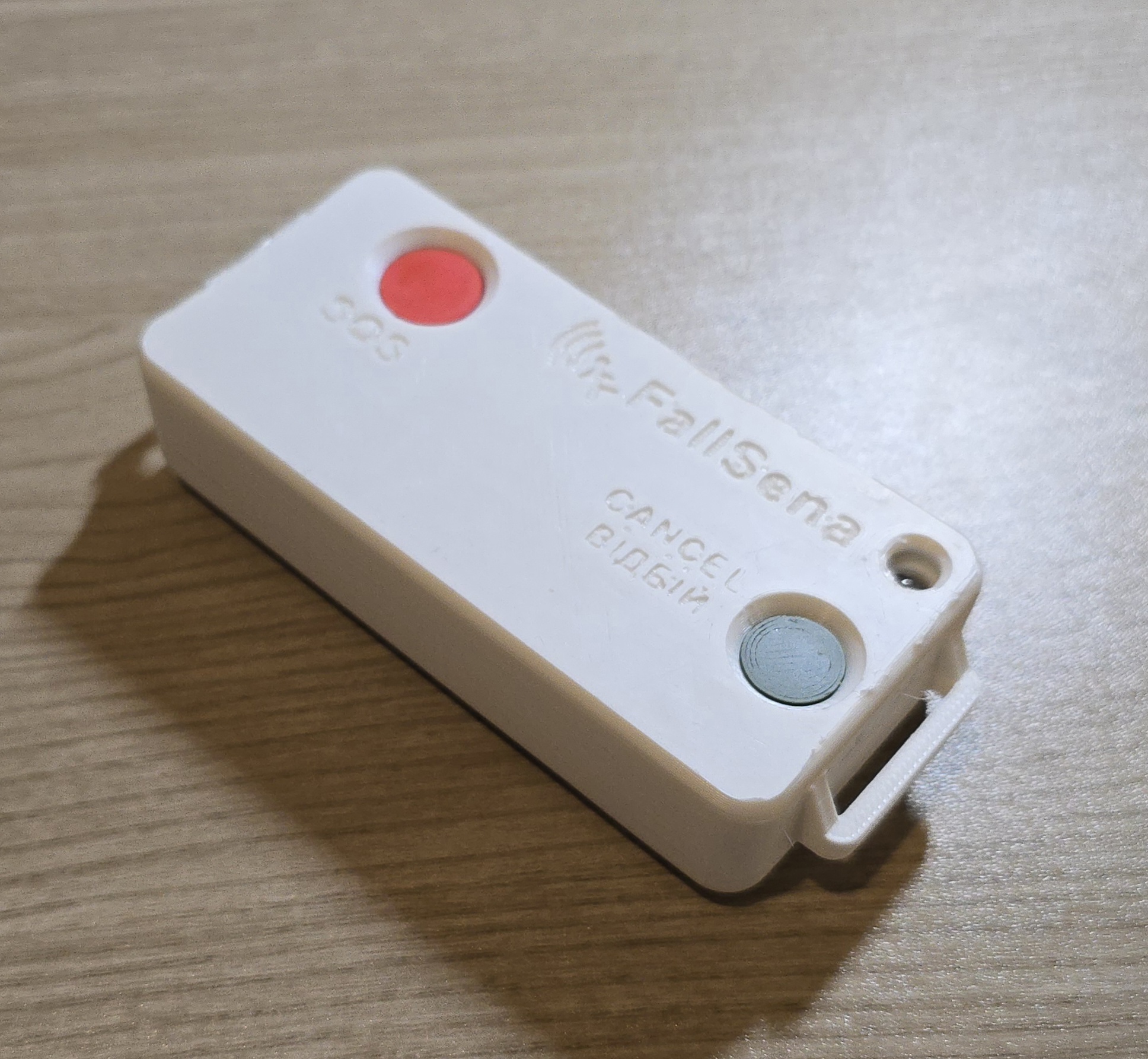 The assembled FallSena device: a white enclosure with a red SOS button, a grey Cancel button, and the FallSena logo on the lid